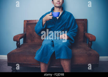 Young man in bathrobe drinking coffee at home Stock Photo