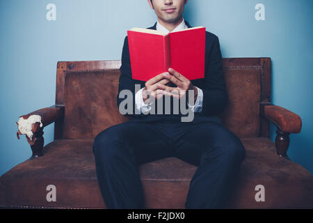Young businessman sitting on sofa and reading Stock Photo