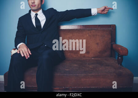 Young businessman sitting on sofa and pointing Stock Photo