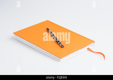 Orange note book with pen on white background Stock Photo