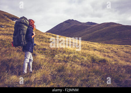 young woman backpacking through wilderness with mountains Stock Photo