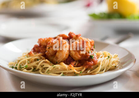Meal of Italian king prawns in tomato sauce on spaghetti served on plate in an italian restaurant. Stock Photo