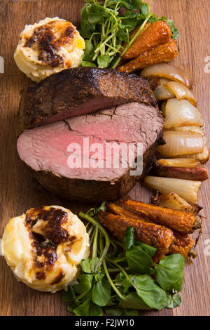 Fillet steak, dauphinoise potatoes and parsnips served on a wooden board in a restaurant. Stock Photo