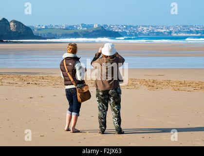two young women taking photographs on the beach at watergate bay in cornwall, uk Stock Photo