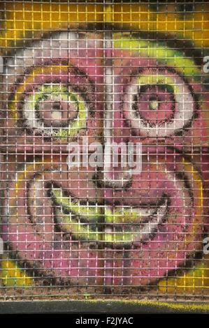 Ugly pink face. Colourful graffiti spray painted on a window shutter. Detail of urban street art by artist known as Loko. Montpellier, South of France. Stock Photo