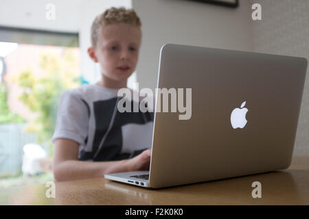 eleven year old boy doing his homework on a macbook laptop computer Stock Photo