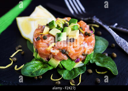 Tasty salmon and avocado tartar, dark background Stock Photo