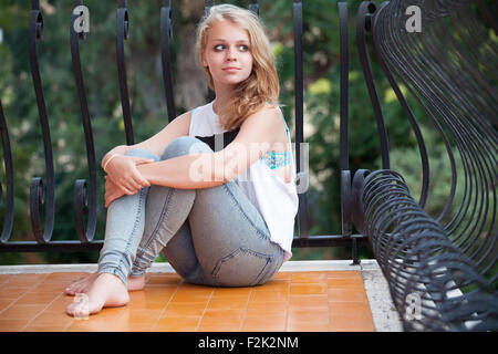 Beautiful blond Caucasian teenage girl on balcony, outdoor summer portrait Stock Photo