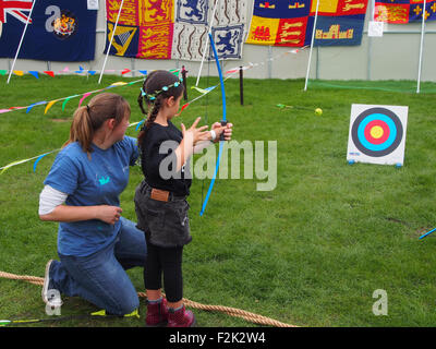 A young child learns about archery from a member of the Mary Rose Trust. Stock Photo