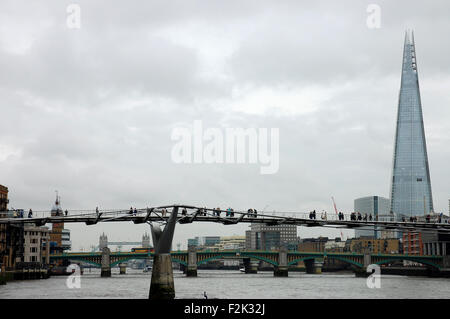 A view along the River Thames in London, encompassing the Millennium Bridge in the foreground and the Shard tower.