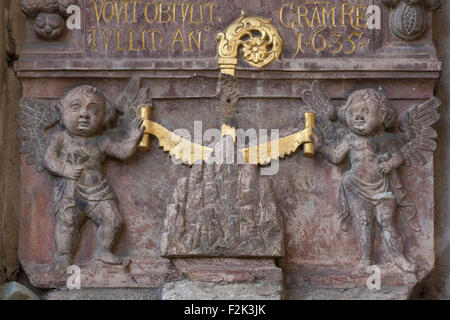 Two angels sawing Mount Montserrat with the golden saw. The medieval stone relief once was installed over the main gate to the Emmaus Monastery (Na Slovanech) in Prague, Czech Republic. The relief commemorates as Benedictine monks arrived from the Montserrat Monastery near Barcelona to Prague in 1635. The sawing scene is the coat of arms of the Montserrat Monastery. The relief is now installed on the outside wall of the cloister of the Emmaus Monastery. Stock Photo