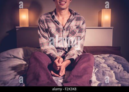 Happy man sitting on bed at night Stock Photo
