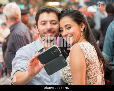 A couple takes a selfie with a smartphone while visiting Times Square in New York City. Stock Photo