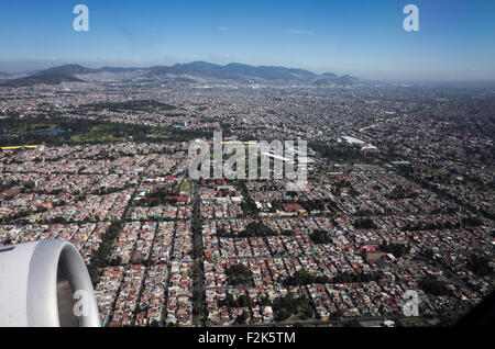 An aerial view of Mexico unfolds beneath the plane, revealing a diverse tapestry of landscapes. From rugged mountain ranges and sprawling deserts to lush forests and winding coastlines, this bird's-eye perspective showcases the country's rich geographical variety. Cities and rural areas alike punctuate the terrain, offering a stunning visual representation of Mexico's natural beauty and human development. Stock Photo