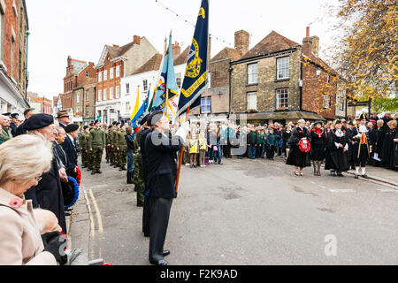 Remembrance Sunday in November. Ex-servicemen and serving soldiers standing at attention while holding flags during cemmemoration ceremony in street. Stock Photo