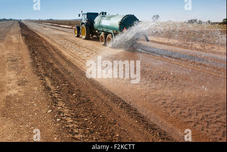 Tractor spreading water in a construction highway Stock Photo