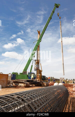 Workers on auto crane and derrick placing pipelines in a construction Stock Photo
