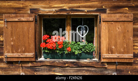 Geraniums and braided heart on the window of a farmhouse, Eng, Eng-Alm, Karwendel, Tyrol, Austria Stock Photo