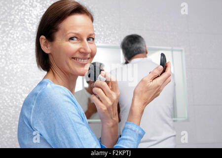 https://l450v.alamy.com/450v/f2kptj/smiling-mature-woman-applying-make-up-on-face-while-her-husband-shaving-f2kptj.jpg