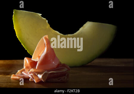 Ham and Melon still life on black background Stock Photo