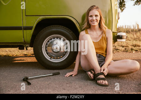 Smiling woman sitting next to a torque wrench at van Stock Photo