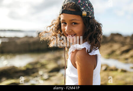Spain, Gijon, portrait of smiling little girl at rocky coast Stock Photo