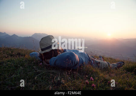 Austria, Tyrol, Unterberghorn, man relaxing on alpine meadow at sunset Stock Photo