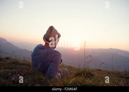 Austria, Tyrol, Unterberghorn, man resting on alpine meadow at sunset Stock Photo