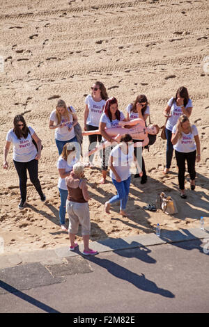 Hen party with bride to be holding blow up doll, the perfect man, on Bournemouth beach in September Stock Photo