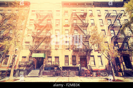 Old film retro style photo of New York building with fire escape ladders, USA.