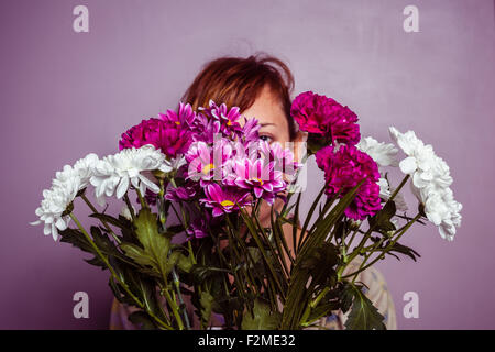 Young woman hiding behind flowers Stock Photo