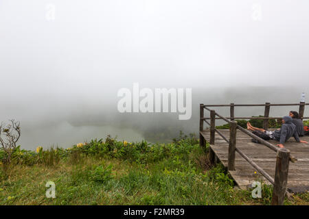 Couple of tourist contemplating the misty Lagoa Funda das Lajes Flores Island,  Azores Stock Photo