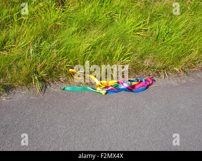 Coloured ribbons lost or dropped on the road, UK. Stock Photo