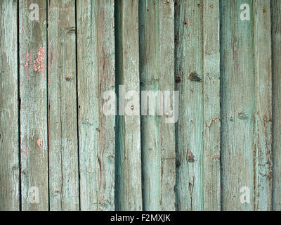Fragment of an old fence with wooden planks covered with green paint peeling off. Stock Photo