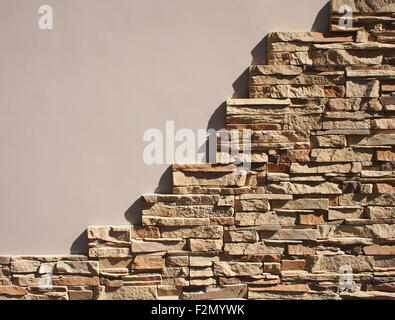 The wall at home with free space beige and decorative mosaics of natural stone in the right lower part of a sharp shadows from t Stock Photo