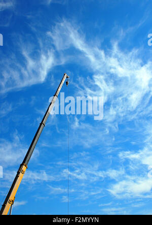 The boom of the crane on a diagonal against a blue sky with white cirrus clouds Stock Photo