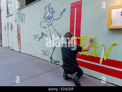 New York, NY 18 September 2015 - French Graffiti artist L'Atlas at work on a mural. His 'abstract calligraphy' creats a strong contrast to the work of French graffiti artist JR and Brasilian Twins Os Gemoes whose work appears on the left. Stock Photo