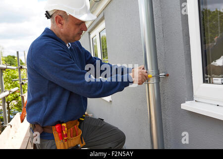 Workman Replacing Guttering On Exterior Of House Stock Photo