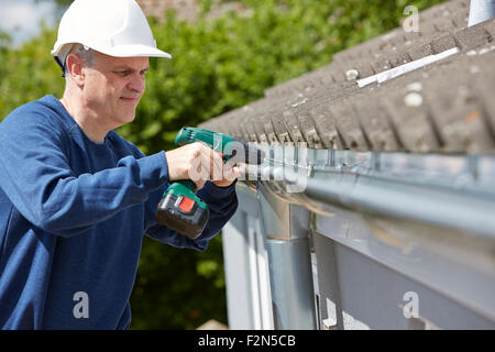 Workman Replacing Guttering On Exterior Of House Stock Photo