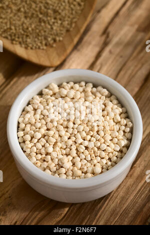 Popped white quinoa (lat. Chenopodium quinoa) cereal in small bowl, raw quinoa grains in the back