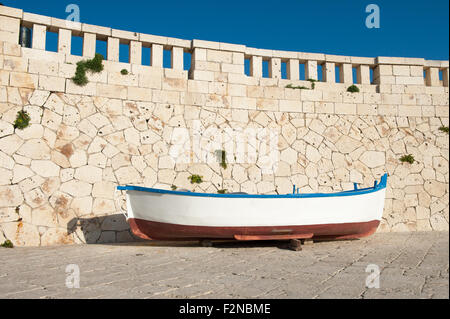 Old boat resting in harbor with stone wall in background Stock Photo