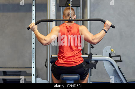 man flexing muscles on cable machine gym Stock Photo
