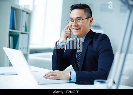 Young Asian businessman in eyeglasses calling in office Stock Photo