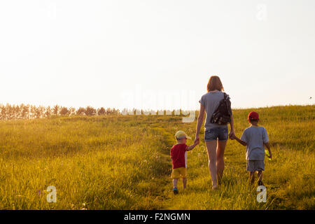 Mother and sons walking in rural field Stock Photo