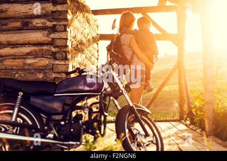 Mother holding son near motorcycle on patio Stock Photo