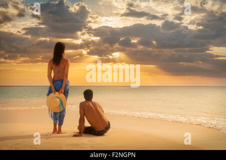 Caucasian couple admiring sunset on beach Stock Photo
