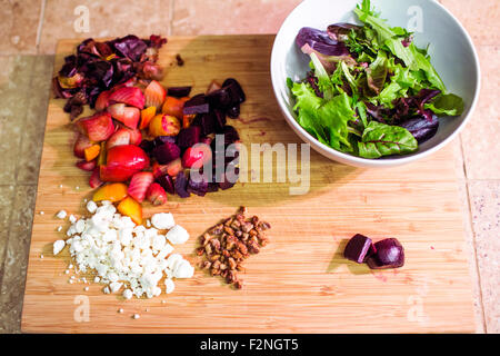 Chopped fruit, nuts and cheese with salad bowl Stock Photo