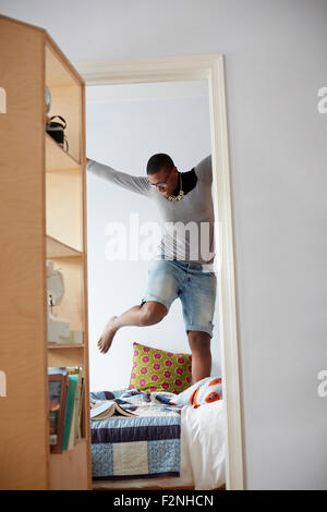 Mixed race woman jumping on bed Stock Photo