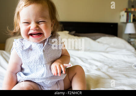 Caucasian baby girl laughing on bed