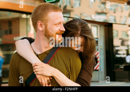 Caucasian couple hugging on city sidewalk Stock Photo